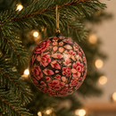 boule de noel avec des fleurs roses peintes à la main, accrochée à une branche de sapin